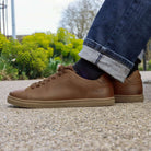 model sitting on bench wearing rowan cognac barefoot shoes with blue jeans