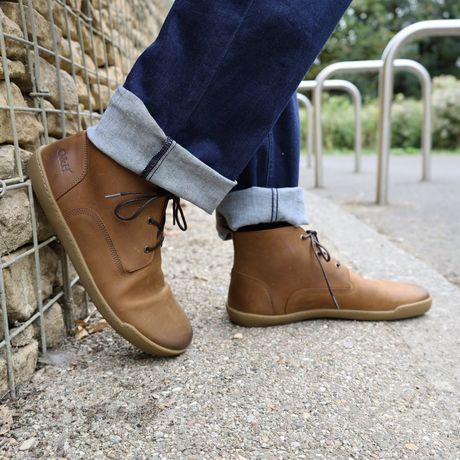 model standing outdoors wearing spruce barefoot ankle boots in tan with blue jeans