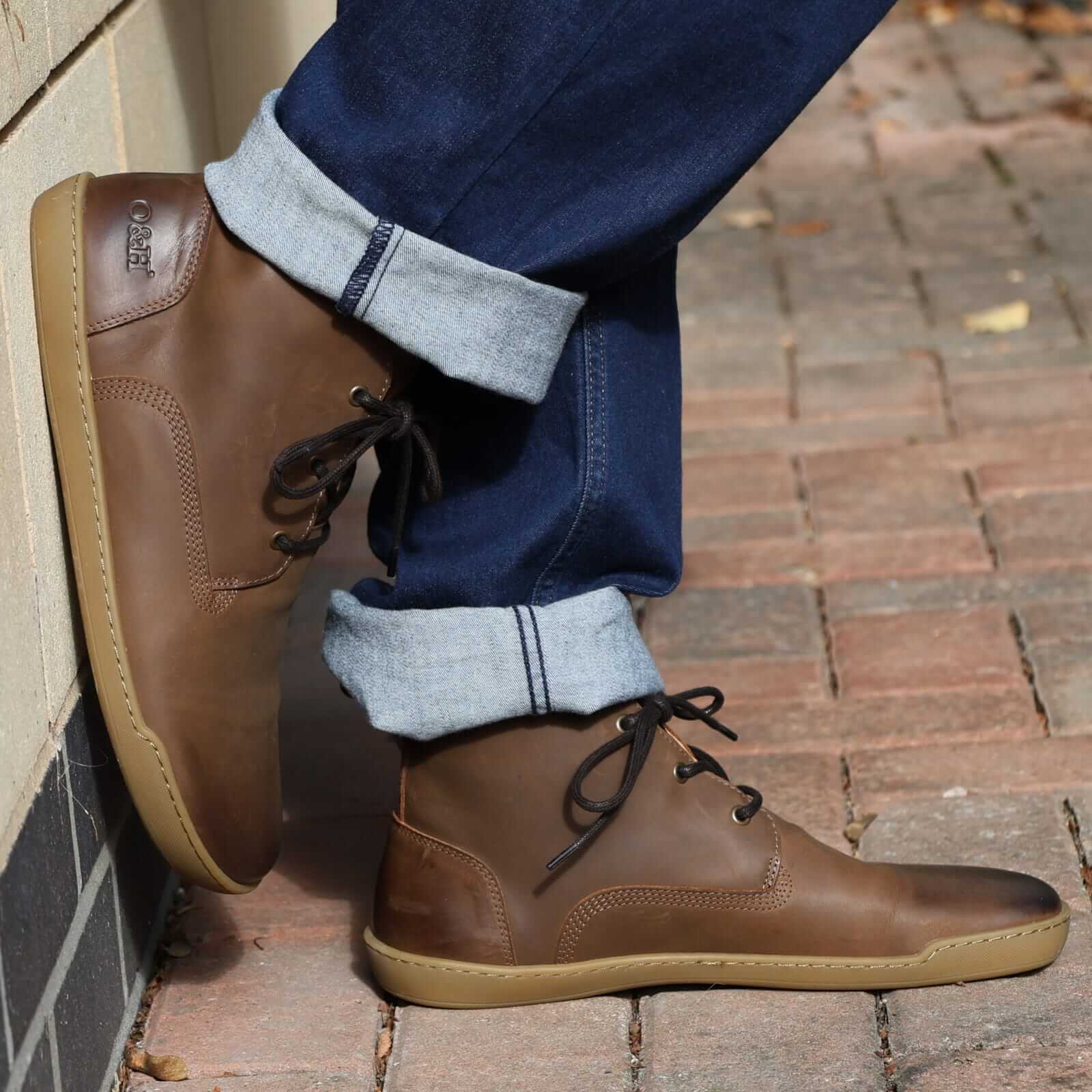 model wearing spruce barefoot boots with blue jeans leaning against a wall