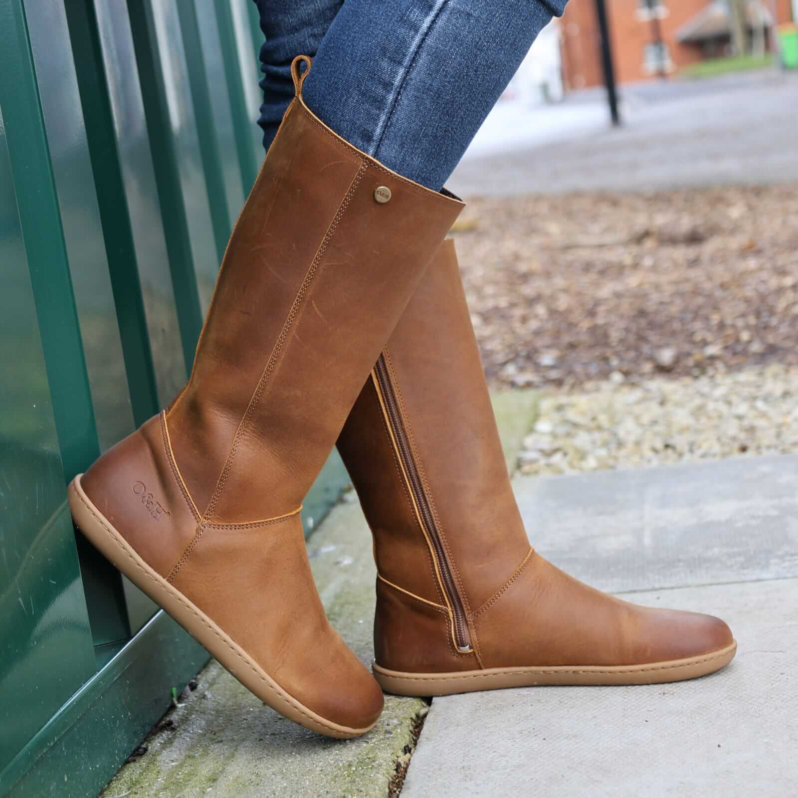 model wearing mid calf tan barefoot boots with blue jeans on concrete floor