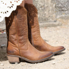 Brown leather cowboy boots on a textured ground surface