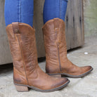 Brown leather cowboy boots with stitched detailing worn with jeans