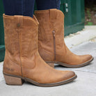 model wearing texan lo cowboy boots in tan with dark blue jeans on pavement
