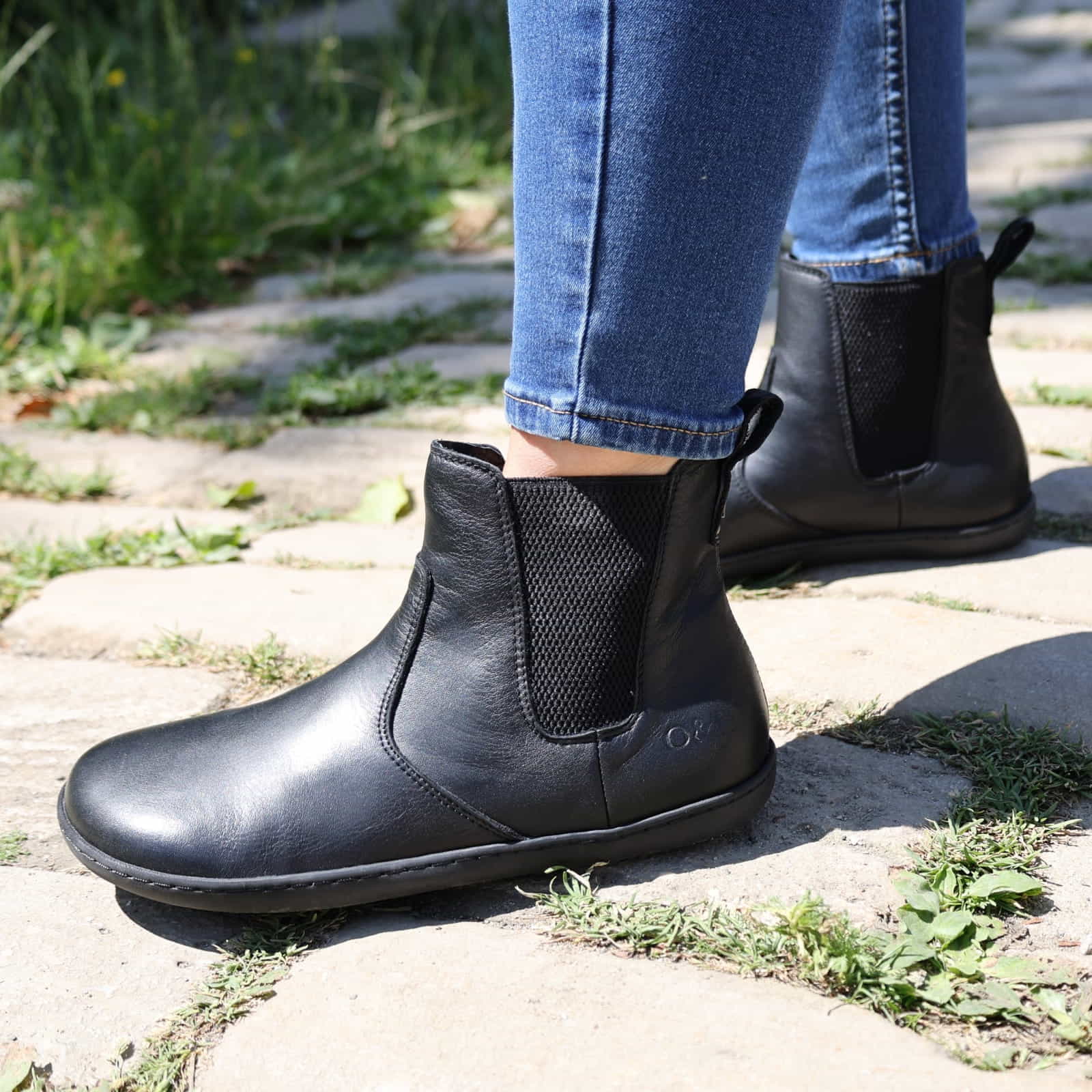 model wearing black barefoot chelsea boots on stone path outdoors