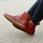 model wearing willow 2 barefoot chelsea boots in red sitting on a bench