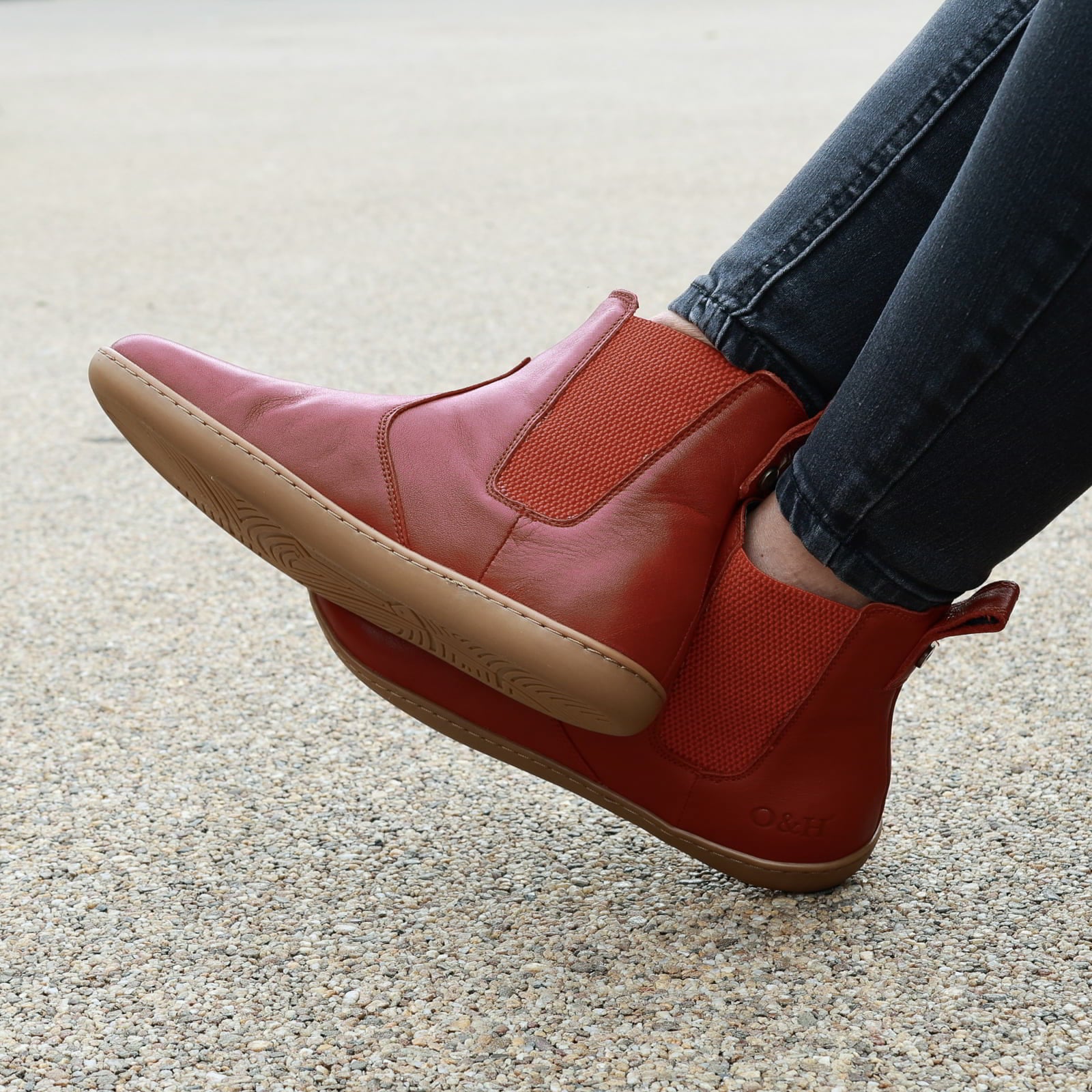 model wearing willow 2 barefoot chelsea boots in red sitting on a bench