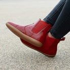 model wearing willow 2 barefoot chelsea boots in red sitting on a bench