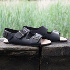 pair of wisteria barefoot sandals in black on a wooden beam showing leather upper