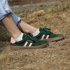 model wearing womens larch barefoot trainers in green pink sitting outdoors