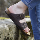 dark brown oak & hyde malaga adjustable sandals worn outdoors on stone steps with rolled jeans